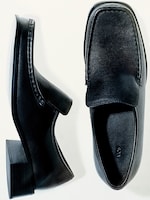 Placeholder for: Two black leather loafers with square toes displayed on a white background, one on its side and the other from above.