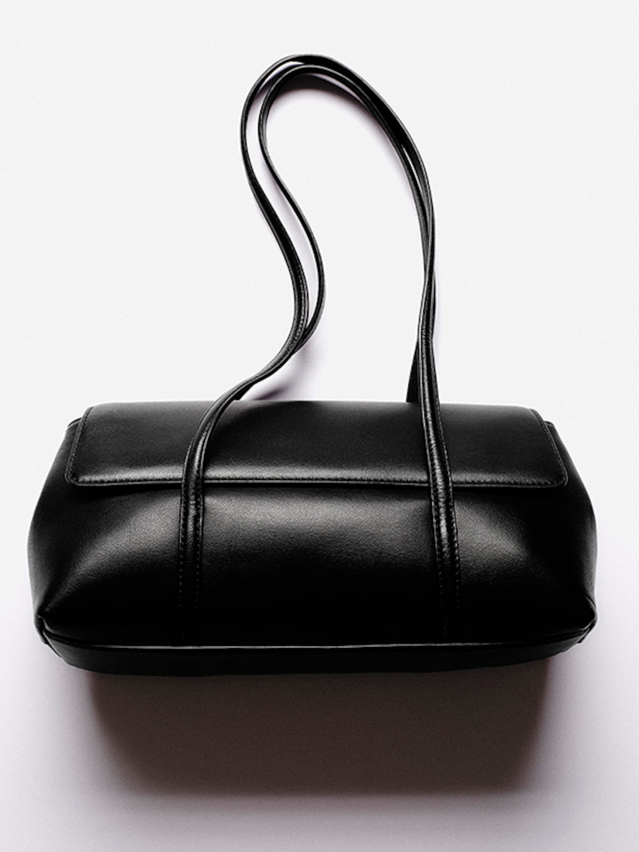 Elegant black leather handbag with long handles on a plain white background.