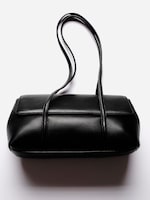 Placeholder for: Elegant black leather handbag with long handles on a plain white background.