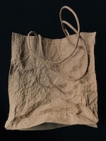 Placeholder for: Crinkled beige tote bag with two handles against a dark background.