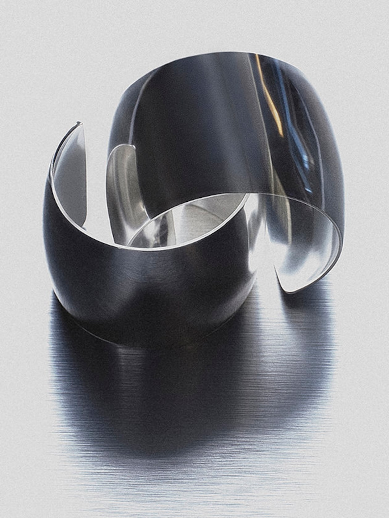 Two sleek, reflective metallic rings, artistically arranged on a brushed metal surface.