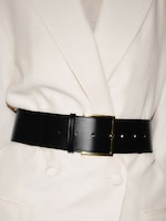 Placeholder for: A black leather belt with a gold buckle cinches a white double-breasted coat, highlighting the tailored waistline.
