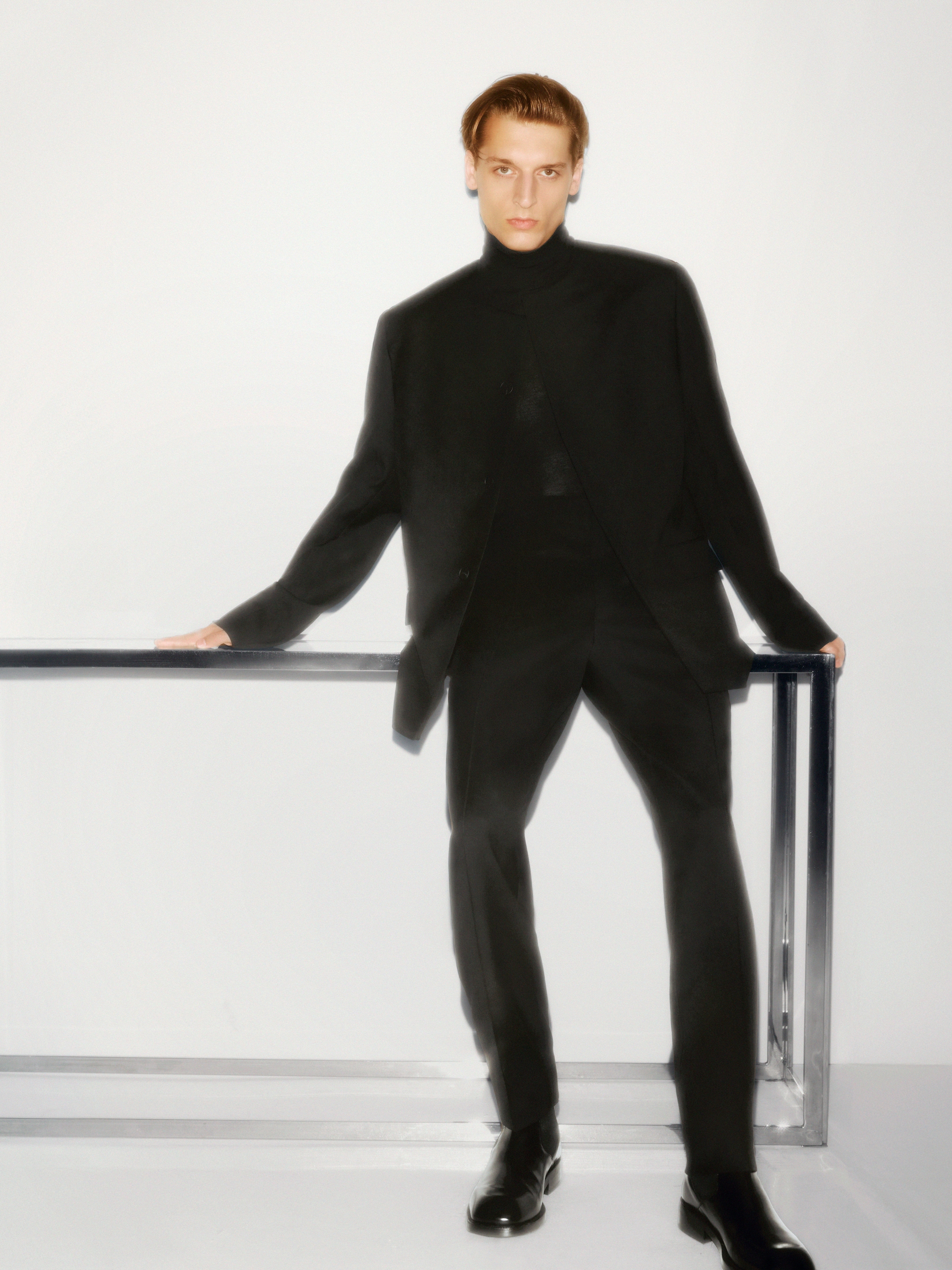 man leaning on a table in a dark suit