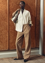 Placeholder for: Woman standing in green striped shirt with brown trousers