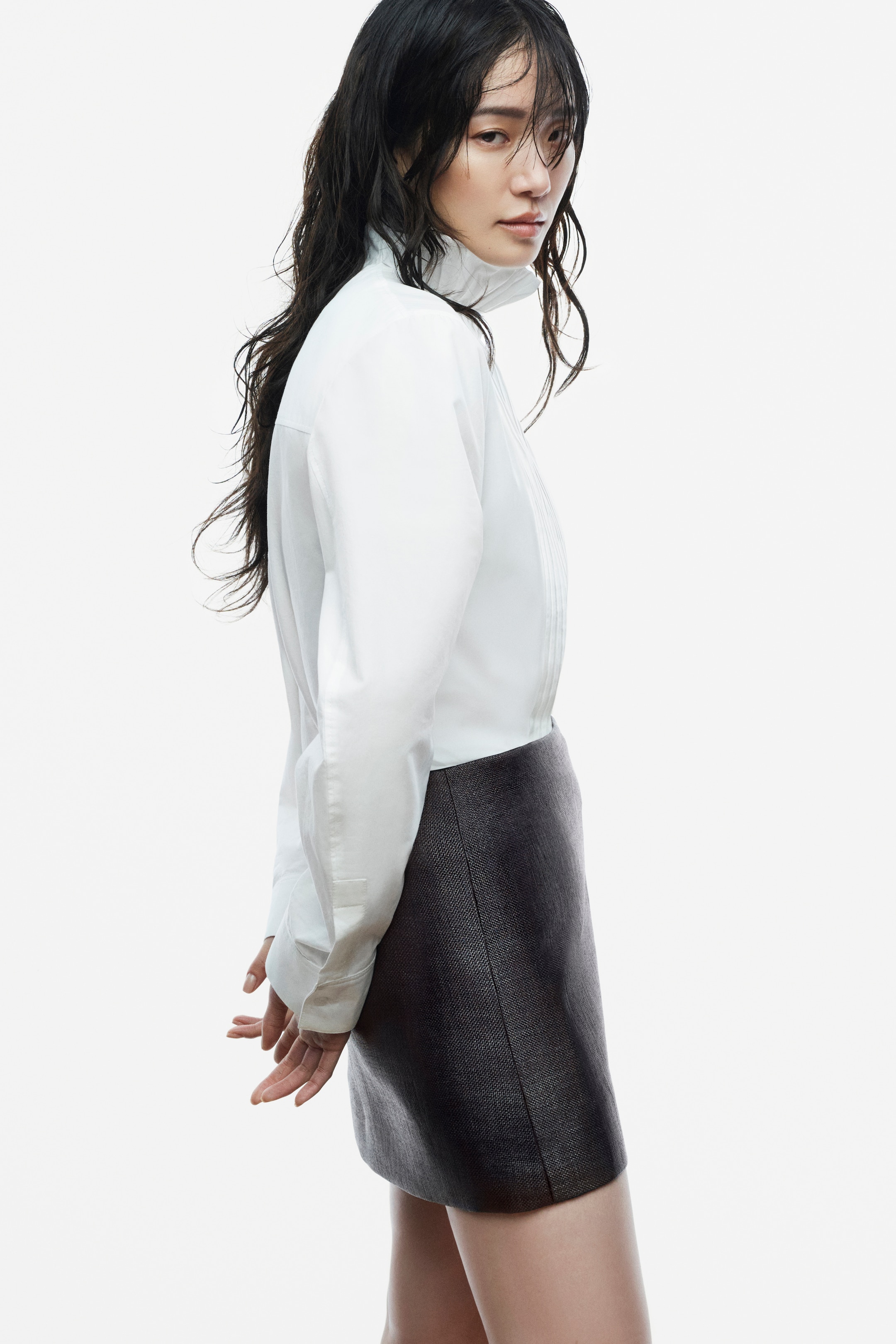 Black and white photo of a person with wet hair, wearing a dark jacket and looking over their shoulder with a serious expression.