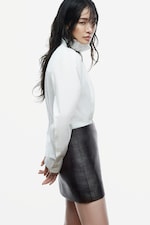 Placeholder for: Black and white photo of a person with wet hair, wearing a dark jacket and looking over their shoulder with a serious expression.