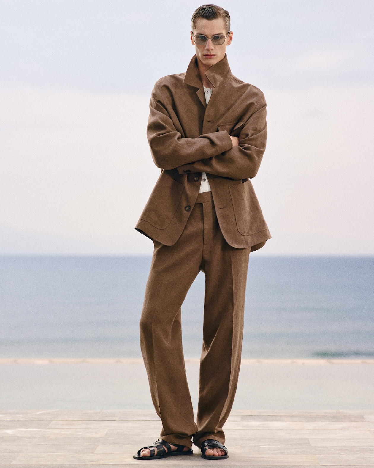 Person in sunglasses wearing a brown suit and sandals