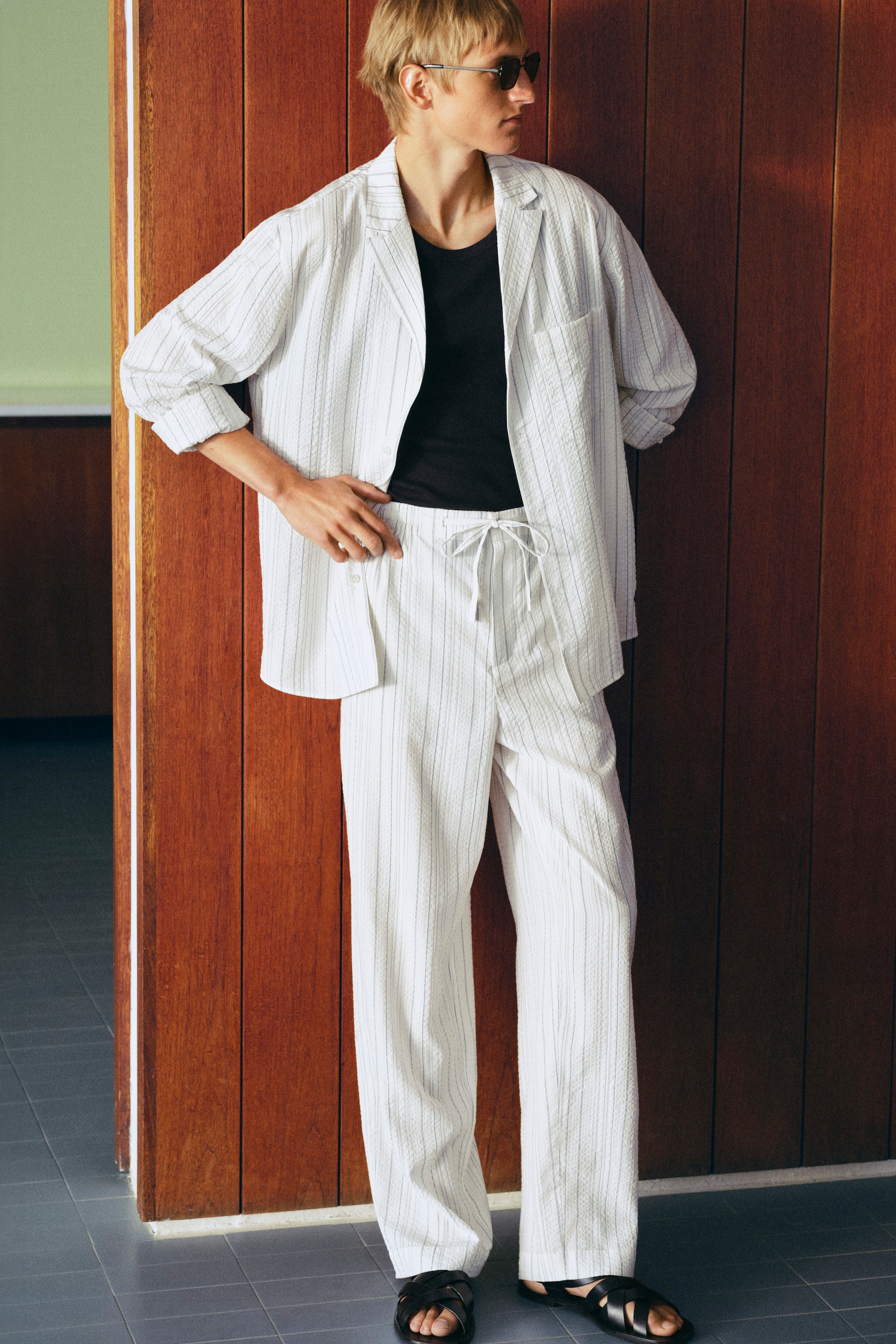 person standing wearing a white stripes seersucker shirt and matching trousers