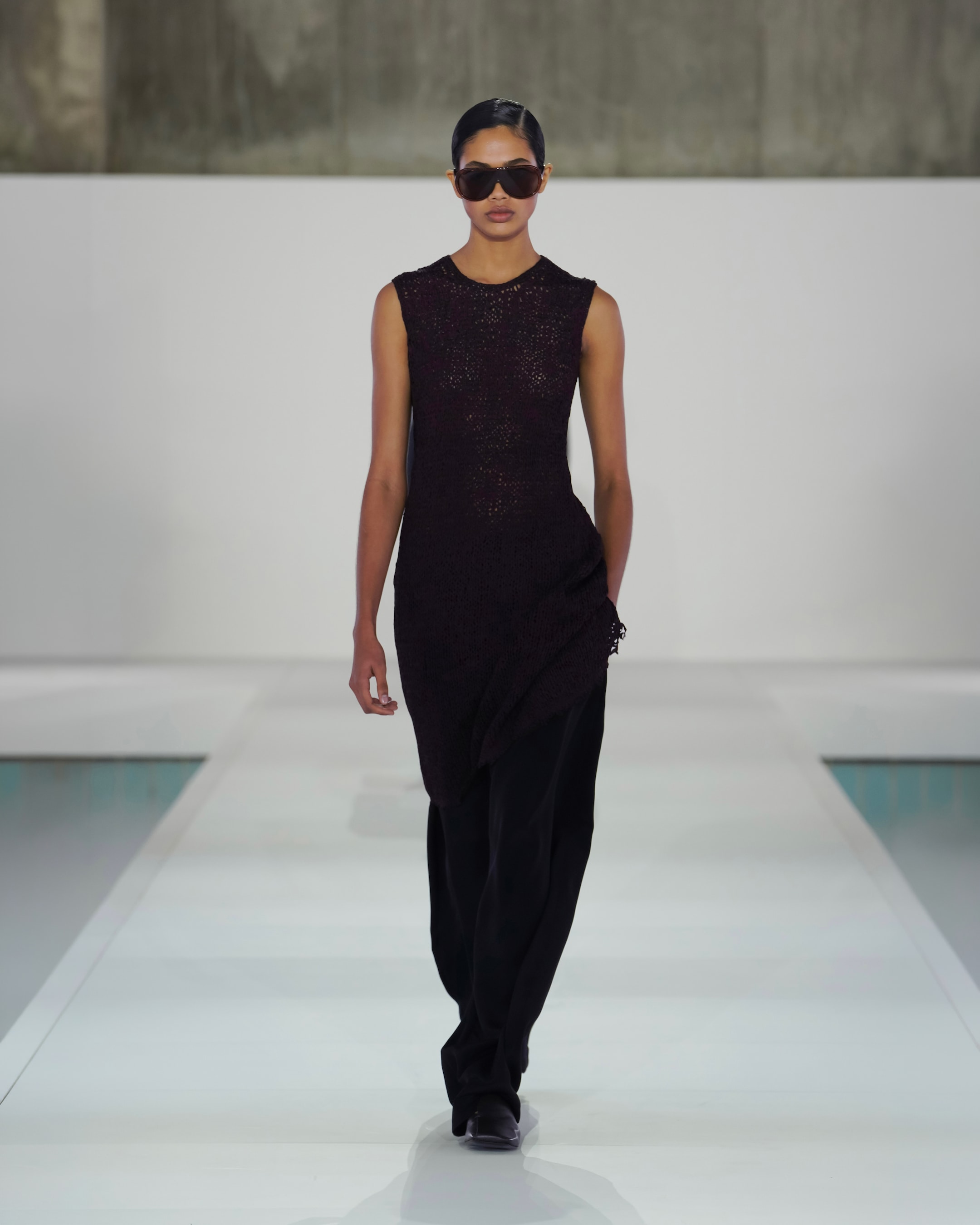 woman in brown sleeveless top black trousers and sunglasses