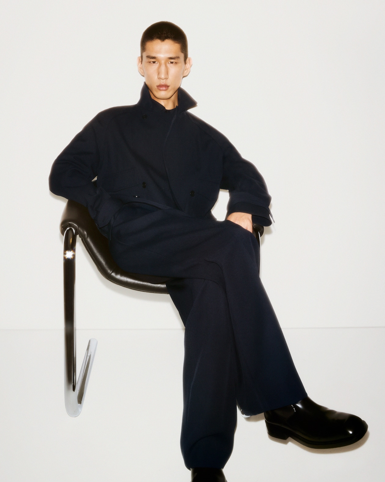 Man sat down with roll up jacket and boots in black