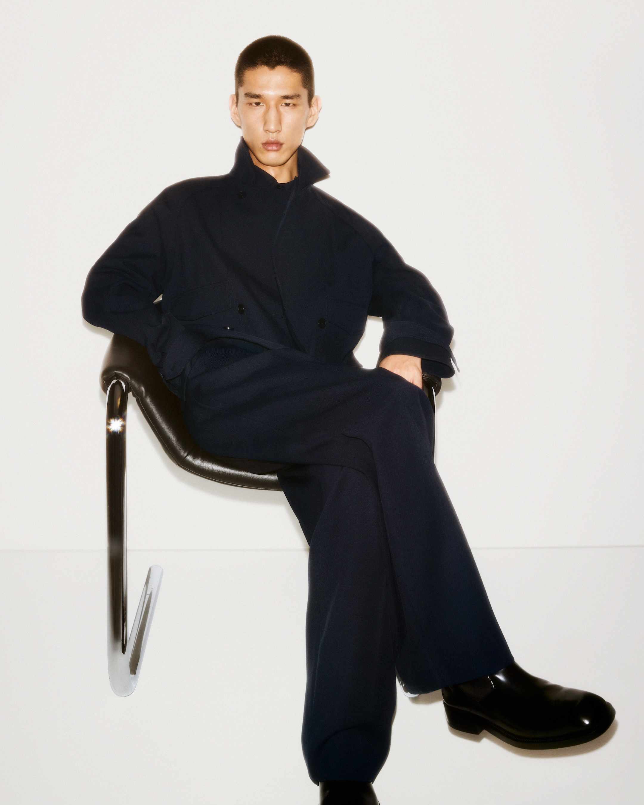 Man sat down with roll up jacket and boots in black