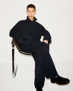 Placeholder for: Man sat down with roll up jacket and boots in black