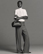 Placeholder for: Woman in blouse and trousers with arms crossed