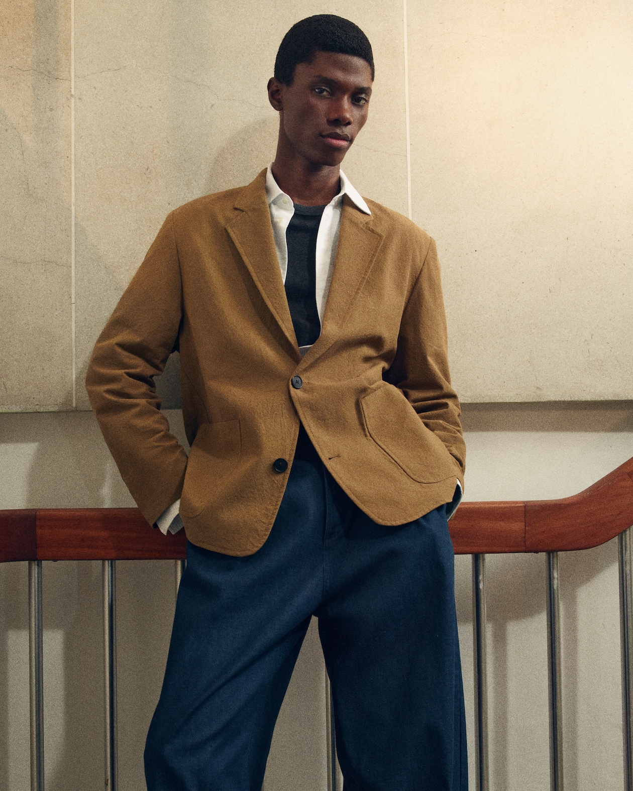 man in blue jeans and brown blazer