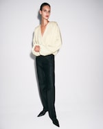 Placeholder for: Person wearing black trousers and beige blouse