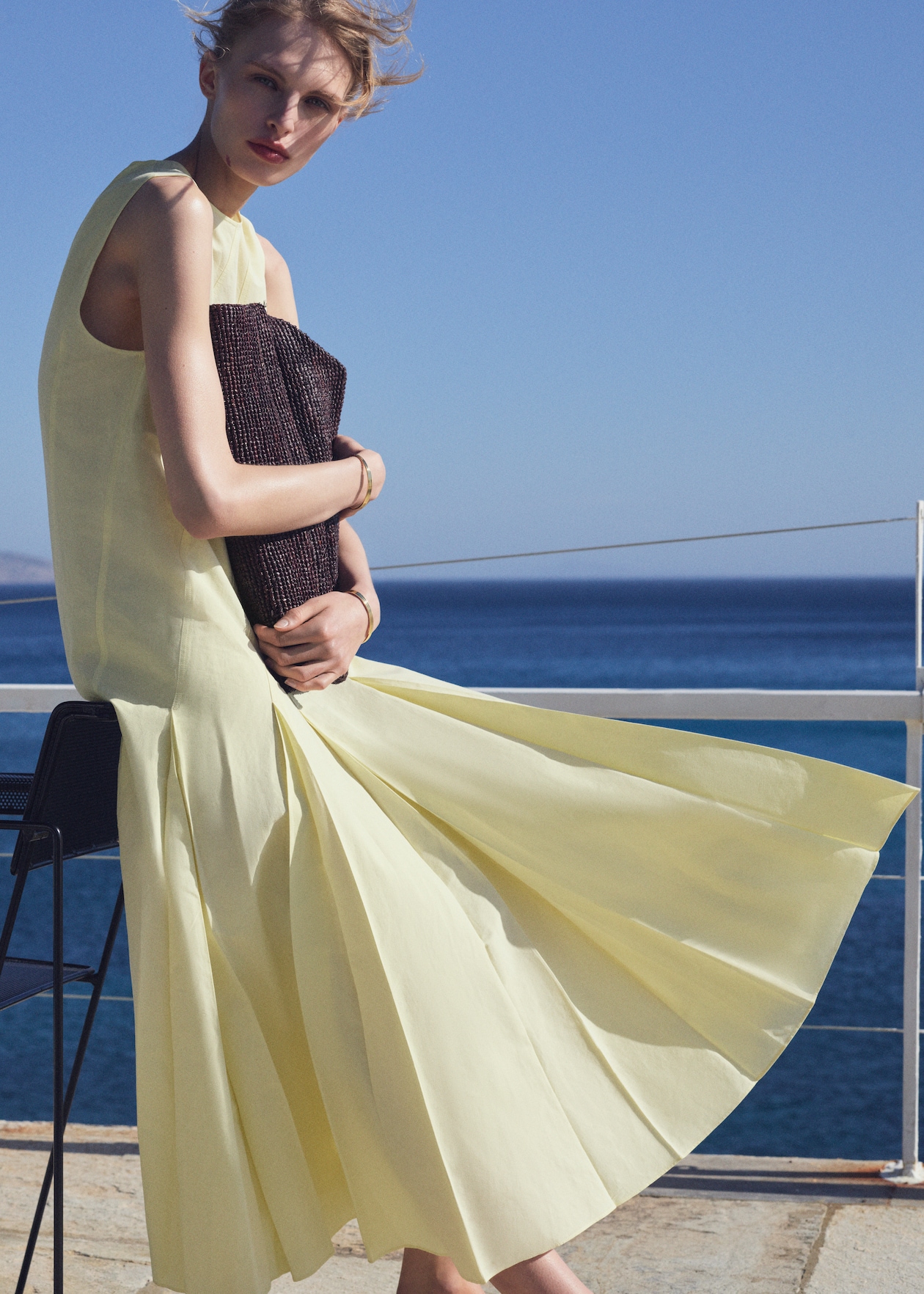 Woman in yellow dress with woven clutch bag