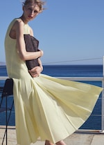 Placeholder for: Woman in yellow dress with woven clutch bag