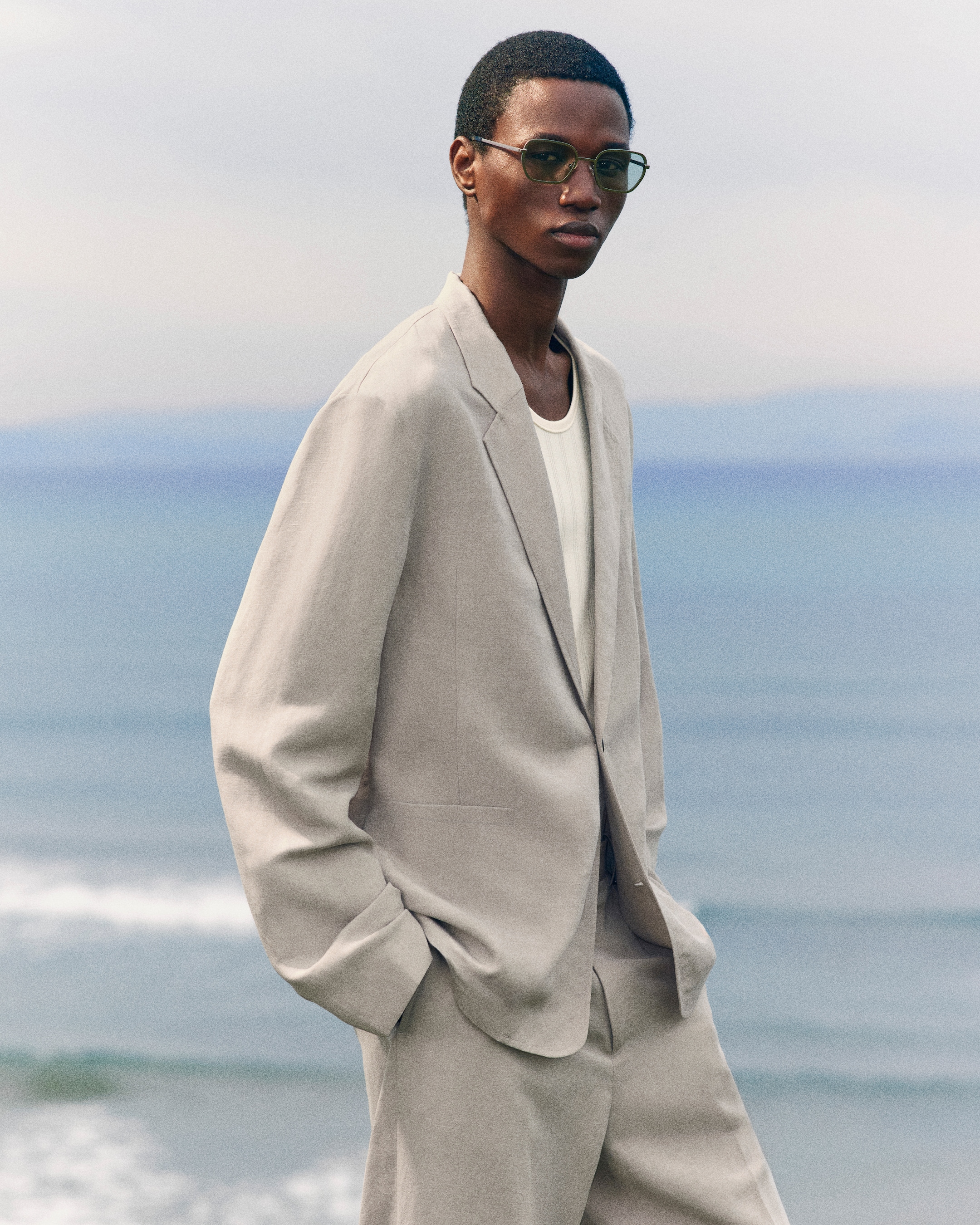 person wearing a light coloured linen blazer and sunglasses