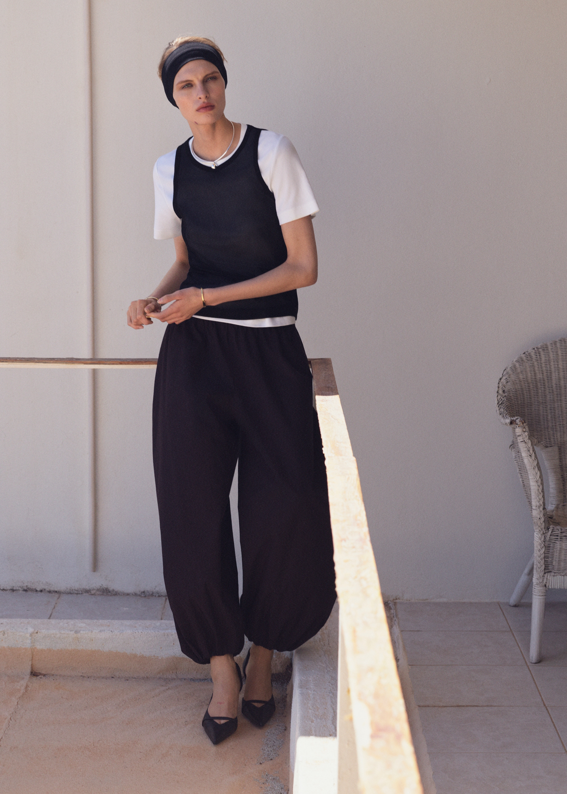 woman in white tshirt, navy tank top and black balloon trousers