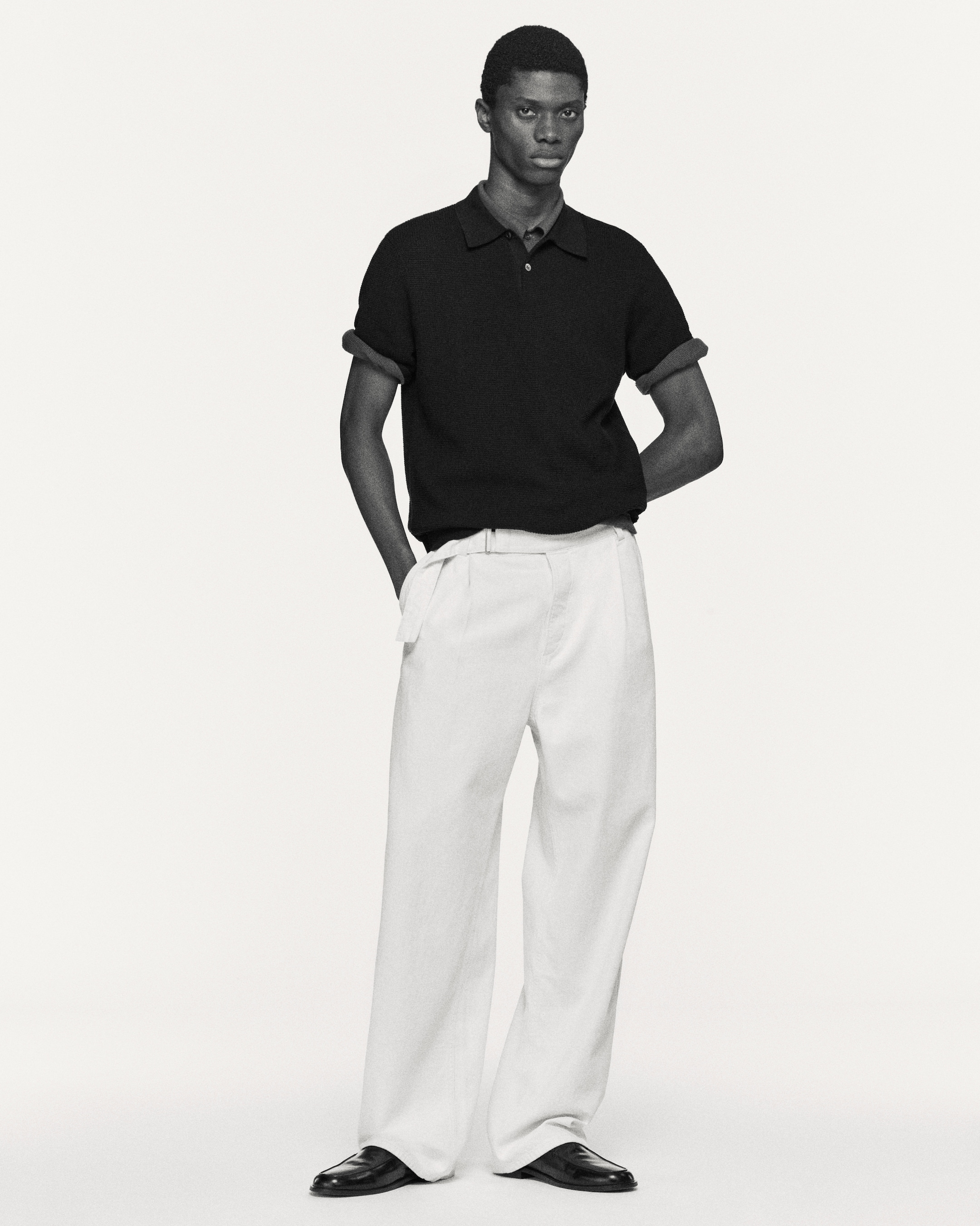 man wearing navy polo shirts and white relaxed denim trousers