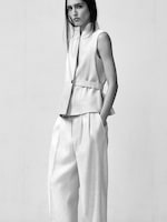 Placeholder for: A person wearing a tailored sleeveless top and wide-legged pants in a minimalist setting.