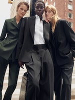 Placeholder for: Three individuals pose in stylish, oversized suits on a city street, exuding confidence and modern sophistication.