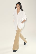 Placeholder for: A person with long hair models wearing a white shirt and beige flared pants, walking confidently with hands in pockets.