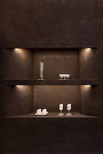 Placeholder for: A dimly lit display shelf showcases modern, minimalist jewelry against a dark textured wall, with subtle lighting highlighting each piece.