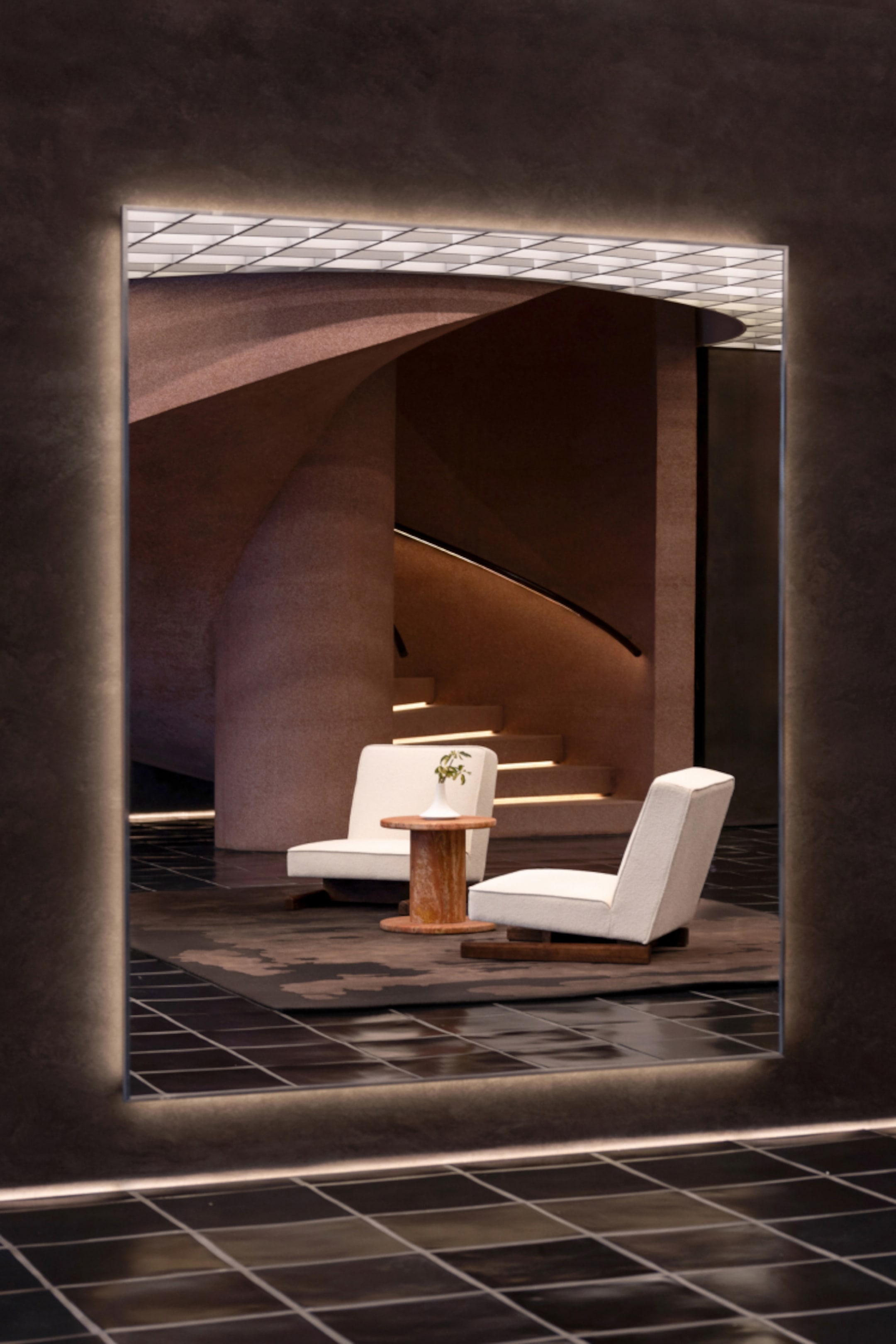Modern interior with two white chairs and a small wooden table near a spiraling staircase, set against a dark, reflective wall.