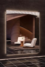 Placeholder for: Modern interior with two white chairs and a small wooden table near a spiraling staircase, set against a dark, reflective wall.