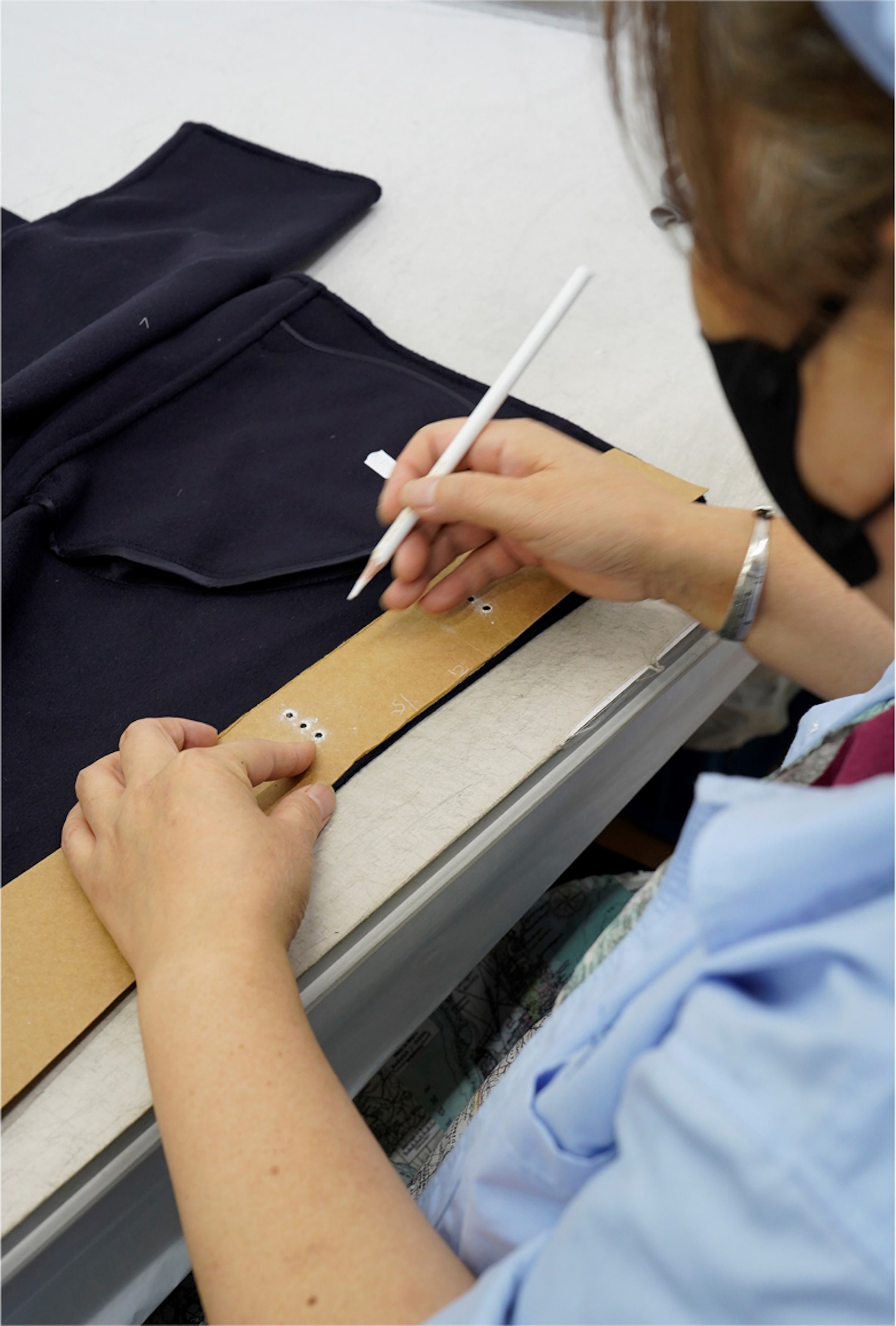 Person marking fabric with a pencil through a cardboard template, preparing for sewing.