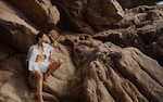 Placeholder for: model on a beach rock wearing bikini and striped shorts and short sleeves opened shirt