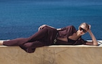 Placeholder for: Woman lying down next to the sea in red jersey set