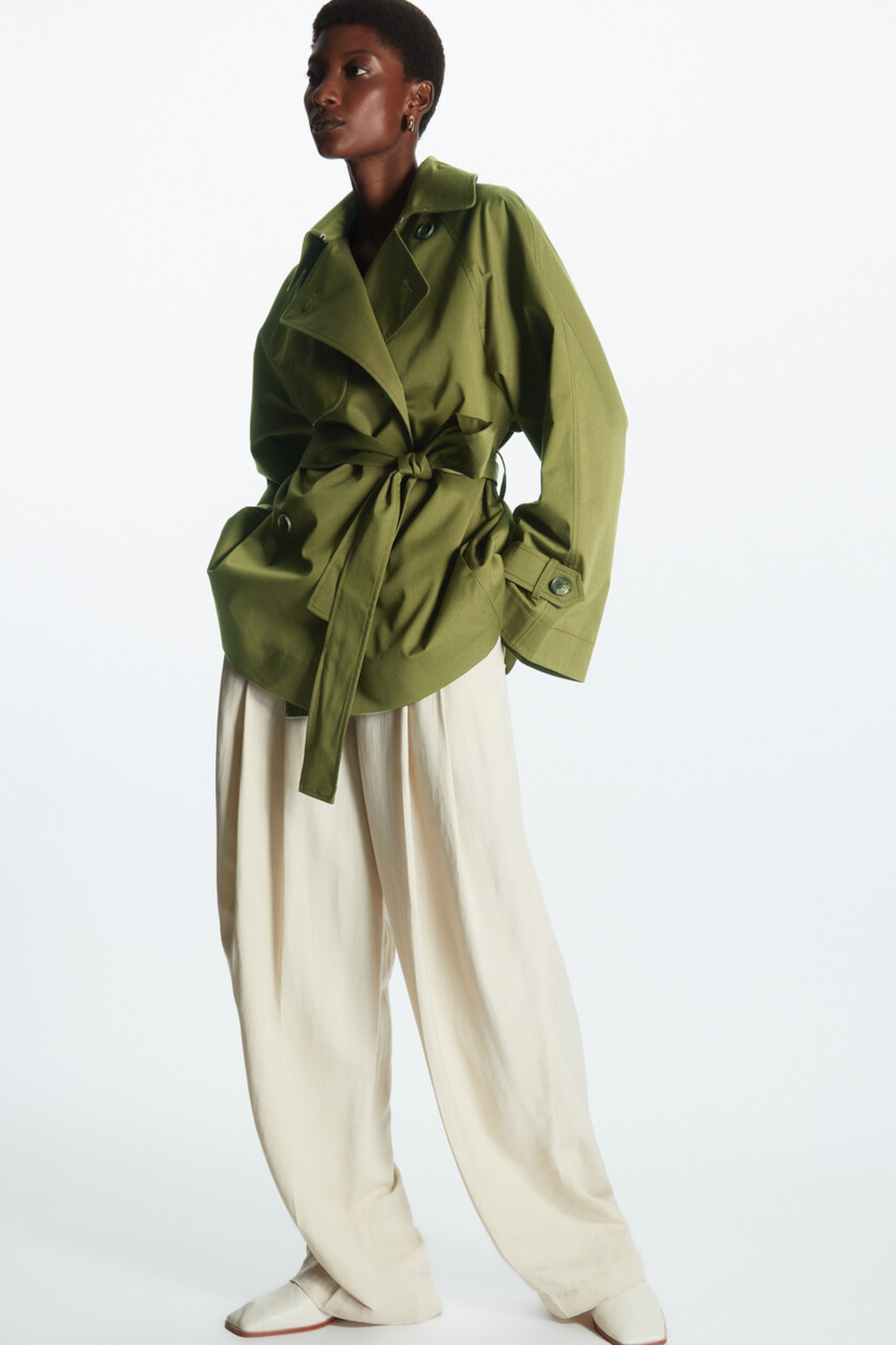 Woman wearing green trench tied across the waist